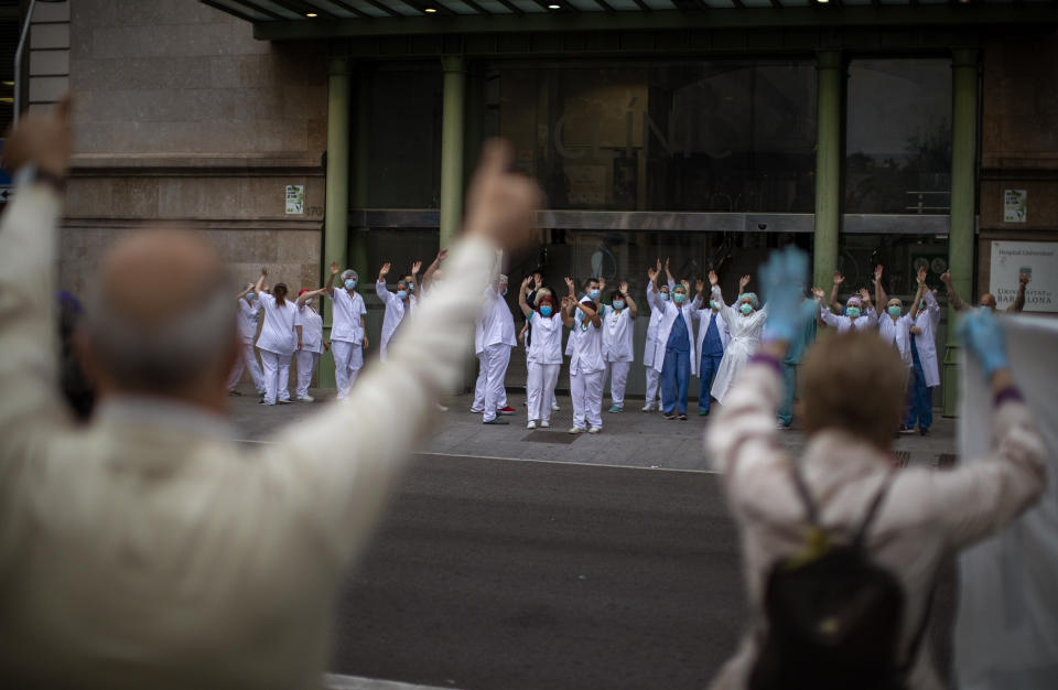 Health workers react as people applaud in the street in support of the medical staff working during the coronavirus outbreak, at the main gate of the Hospital Clinic, on International Nurses Day, Tuesday, May 12, 2020 in Barcelona, Spain. Spain has become the first western Europe to accumulate more than 1 million confirmed infections as the country of 47 million inhabitants struggles to contain a resurgence of the coronavirus. (AP Photo/Emilio Morenatti)