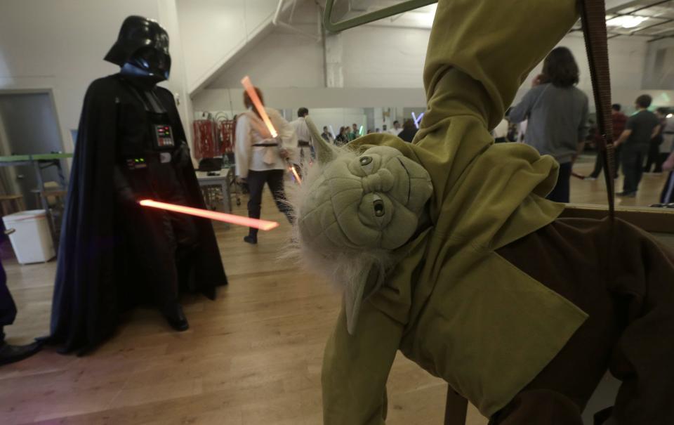 �Gary Ripper, dressed as Darth Vader, walks past a Yoda doll during Golden Gate Knights class in San Francisco, Sunday, Feb. 10, 2013. A group of San Francisco Star Wars fans who want to travel to a galaxy not that far away have created a combat choreography class for Jedis-in-training with their weapon of choice: the light saber. (AP Photo/Jeff Chiu)