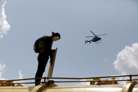 A helicopter flies over a demonstrator on top of a truck blocking a highway during a rally against Venezuela's President Nicolas Maduro's Government in Caracas, Venezuela, June 23, 2017. REUTERS/Ivan Alvarado