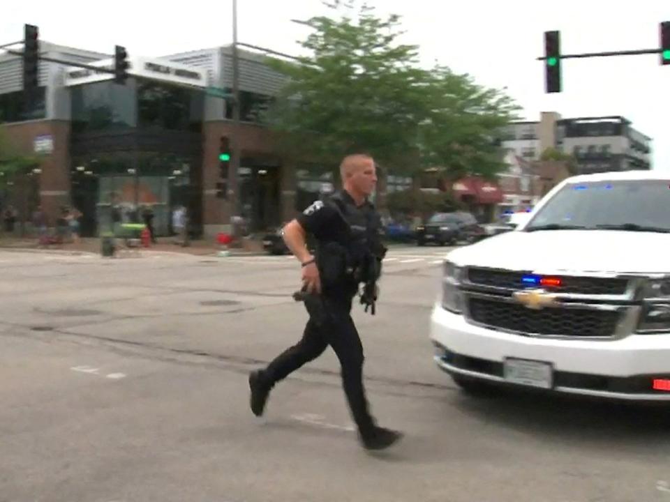 police officer runs across street in front of police car in highland park illinois