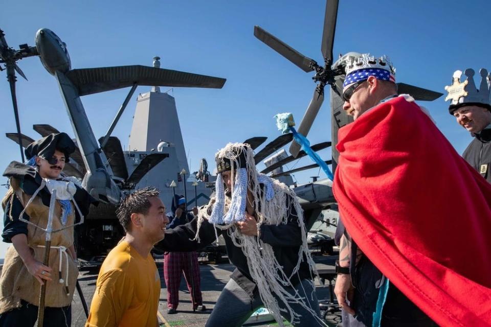 Ensign Sehoon Kim is welcomed into the "Order of the Blue Nose" during an Arctic Circle ceremony on the flight deck of USS Arlington.