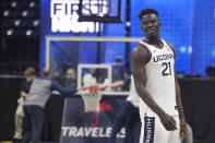 Connecticut's Adama Sanogo watches First Night events for the UConn men's and women's NCAA college basketball teams as people work on a stuck basketball hoop behind him, Friday, Oct. 15, 2021, in Storrs, Conn. (AP Photo/Jessica Hill)