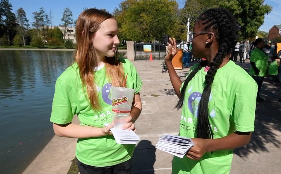 Giuliana Paugh, left, and Kelira Shaw-Burton give out an invite for the public to adopt a storm drain at Kiwanis Lake. The seventh-graders in the Smith STEAM Academy help monitor the lake and use the data generated in the classroom.