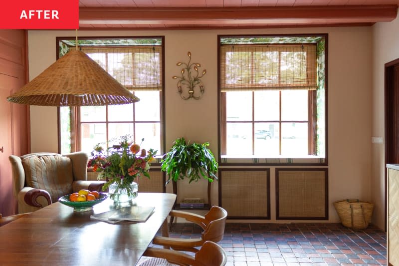 A beige kitchen with a large window and wooden dining table.