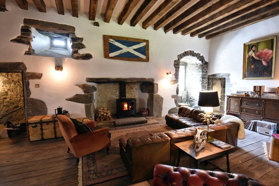 A wide lens photograph of the Grand Hall at Kilmartin Castle, which features a Scottish flag, a painting of a bearded woman and