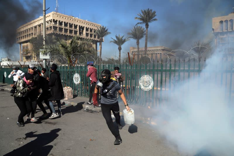 Iraqi demonstrators run from tear gas thrown during ongoing anti-government protests in Baghdad