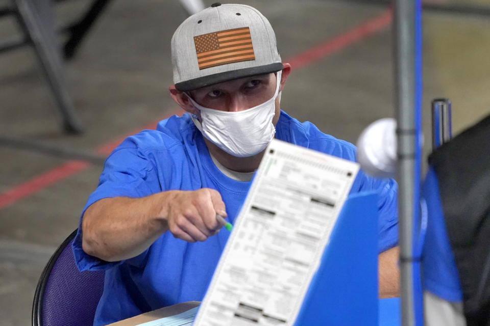 A worker wearing a mask points at a ballot during a recount in Arizona. 