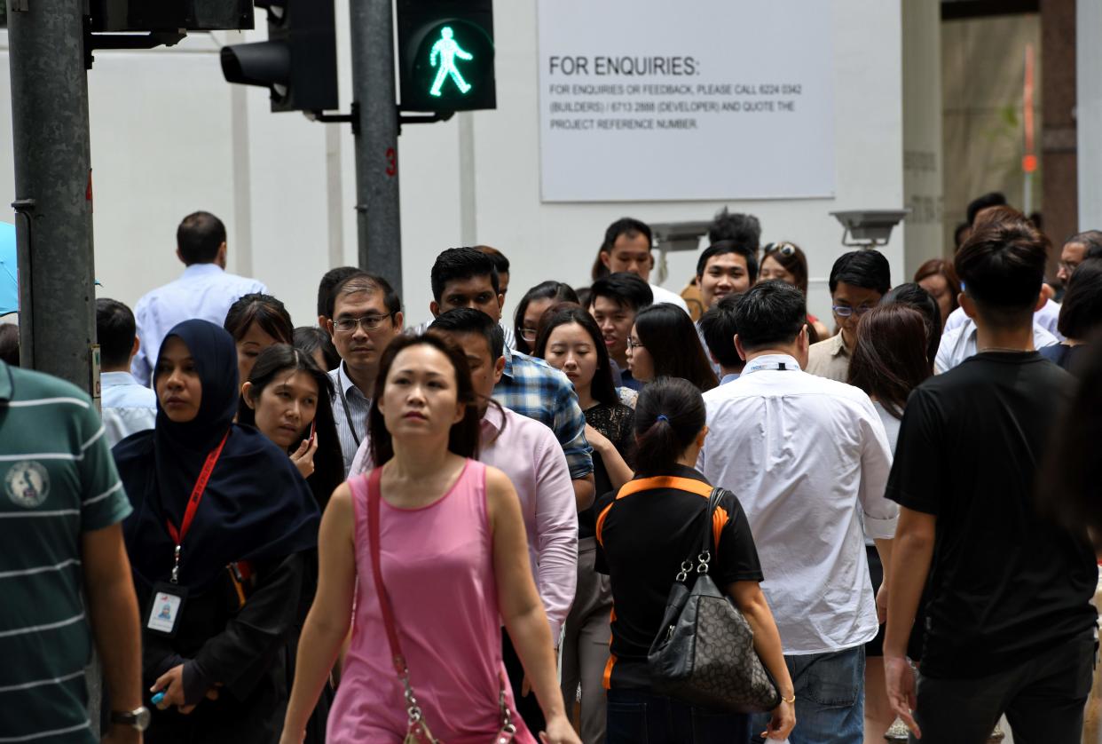 People walk across a zebra crossing at a light in the financial business district in Singapore on 14 February, 2018. (AFP via Getty Images file photo)