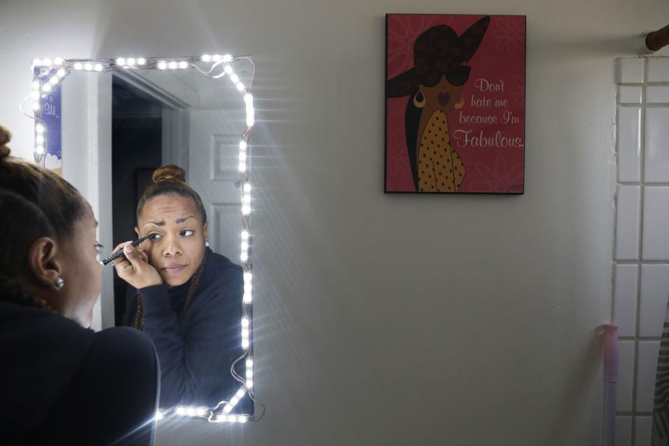 Graham applies eye makeup as she gets ready for work at her studio apartment in Westlake.