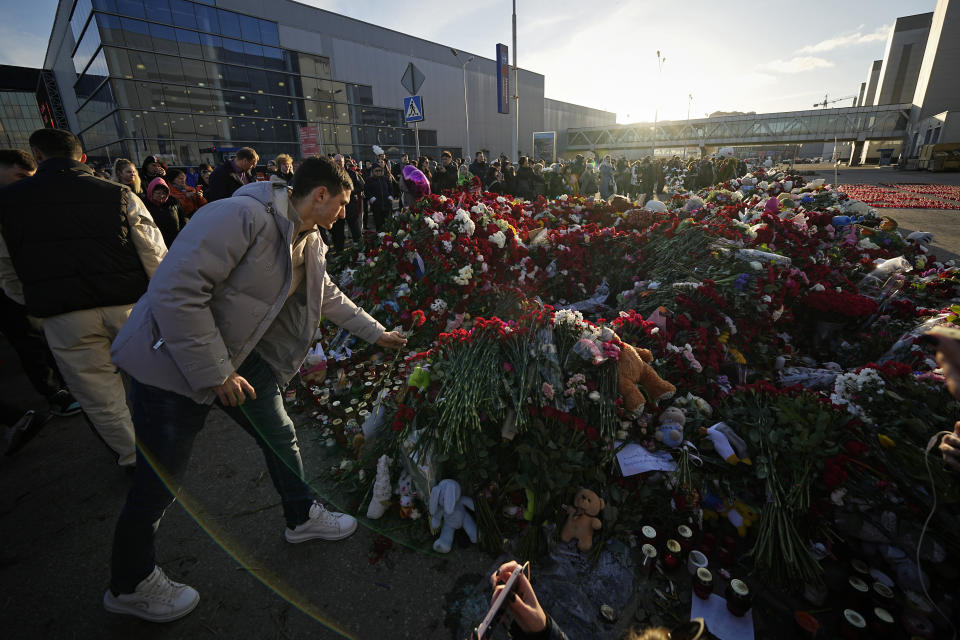 People place flowers at a makeshift memorial in front of the Crocus City Hall on the western outskirts of Moscow, Russia, Monday, March 25, 2024. The four men charged with the massacre at a Moscow theater have been identified by the Russian government as citizens of Tajikistan, some of the thousands who migrate each year from the poorest of the former Soviet republics to scrape out marginal existences. (AP Photo/Alexander Zemlyanichenko)