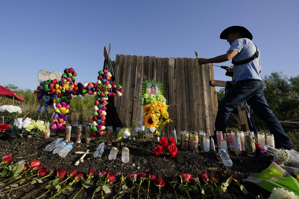 Roberto Marquez, de Dallas, añade una flor el miércoles 29 de junio de 2022 a un altar instalado en el lugar donde agentes hallaron a docenas de migrantes muertos en un tractocamión abandonado en San Antonio. (AP Foto/Eric Gay)