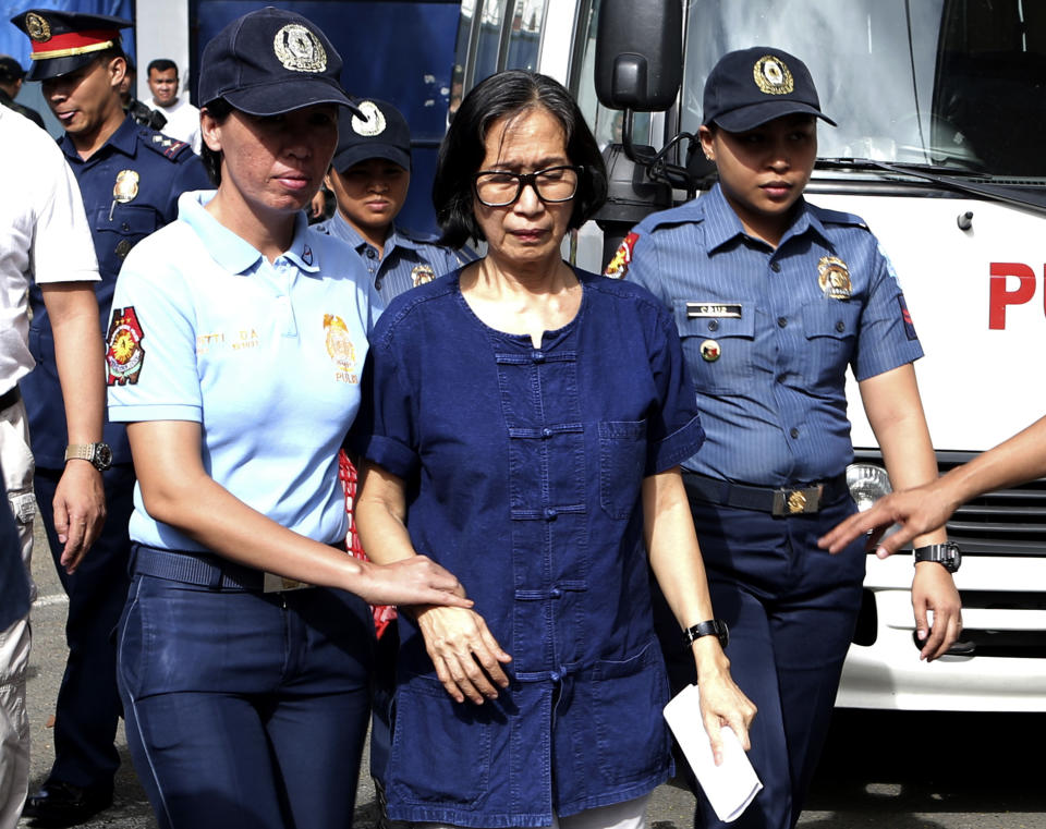 In this photo released by the Philippine National Police Public Information Office, suspected communist leader, Wilma Austria Tiamzon, is escorted as she arrives at the Camp Crame police headquarters in suburban Quezon city, north of Manila, Philippines on Sunday, March 23, 2014. Philippine officials said Sunday that they would not release two leaders of a violent rebel group fighting to overthrow the government, whose arrests were a serious blow to one of Asia's longest-running communist insurgencies. (AP Photo/Philippine National Police, Public Information Office)