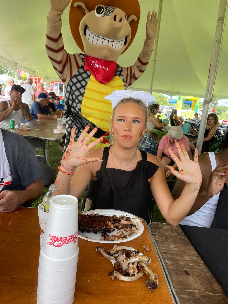 Caroline Matthews, 17, with the Karns High Cheer Team is cheered on by Andy the Armadillo. Matthews didn’t win, but she was the most popular contestant in the rib eating contest sponsored by Texas Roadhouse at the Karns Community Fair at Karns High School Saturday, July 16, 2022.