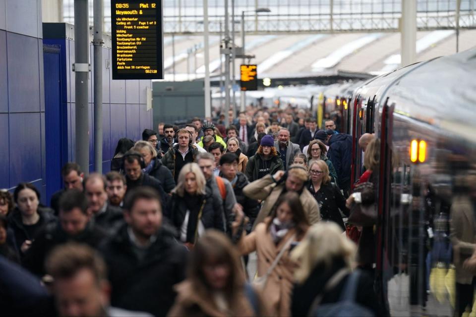 Commuters walk along a platform at Waterloo train station (PA)