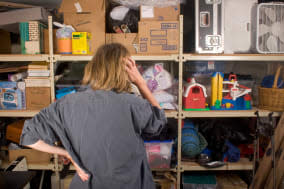 AA8RTT Woman searching through full shelves  woman; searching; full; shelves; accessibility; basket; box; caucasian; chaos; choi