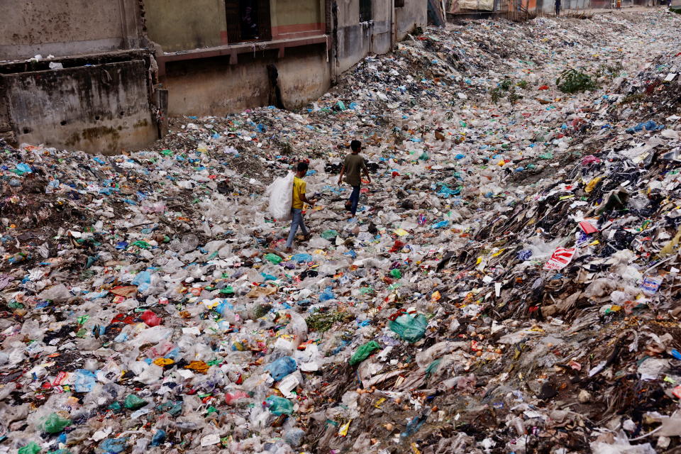 Children walk over a polluted area as they collect plastic materials in Dhaka, Bangladesh, January 24, 2022. REUTERS/Mohammad Ponir Hossain