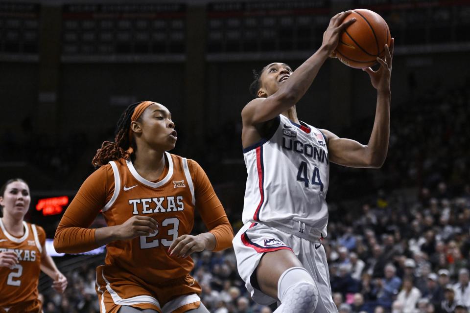 Connecticut's Aubrey Griffin (44) goes up to the basket as Texas' Aaliyah Moore (23) defends during the first half of an NCAA college basketball game, Monday, Nov. 14, 2022, in Storrs, Conn. (AP Photo/Jessica Hill)