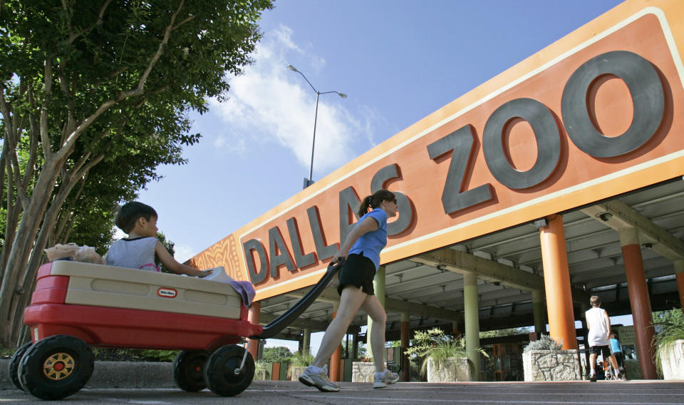 A person pulls a child in a wagon toward the entrance to the Dallas Zoo.