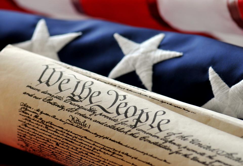 The preamble of the U.S. Constitution lying in front of an American flag.