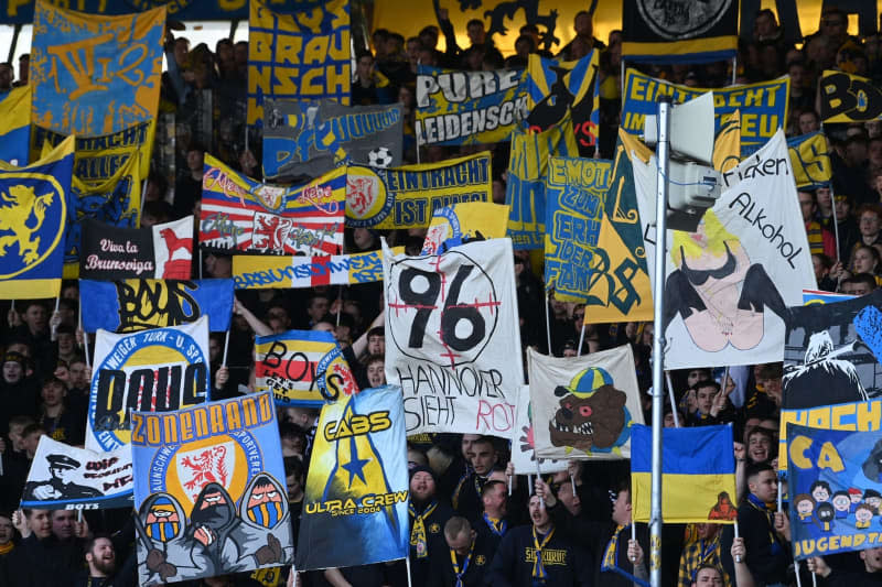 Fans from Braunschweig display posters, including a crosshair with a 96 and the words "Hannover sieht Rot", symbolizing the club Hannover 96 during the German 2. Bundesliga soccer match between Eintracht Braunschweig and Karlsruher SC at Eintracht Stadium. Hanover managing director Martin Kind has said he will take action after fans portrayed him and others on banners with cross-hairs during a match. Swen Pförtner/dpa