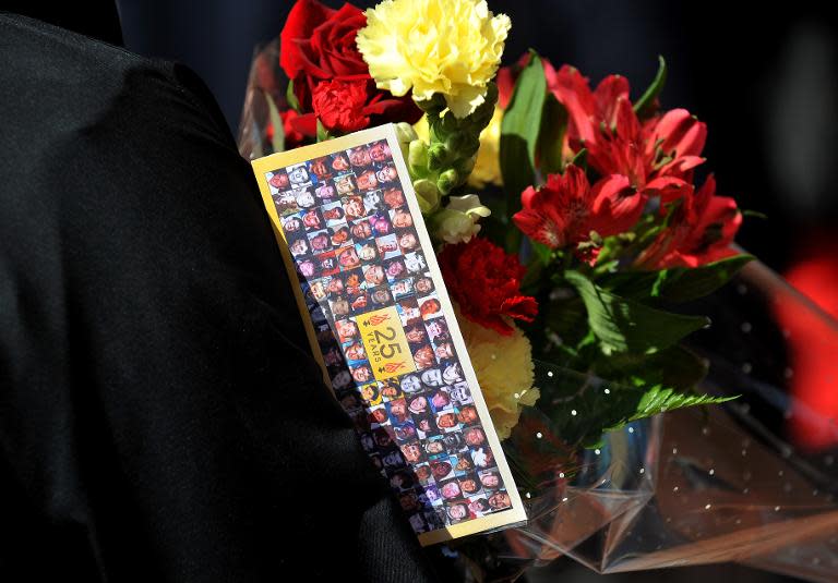 A man carries fowers showing the faces of the 96 victims of the Hillsborough Disaster at Anfield Stadium in Liverpool, northwest England on April 15, 2014