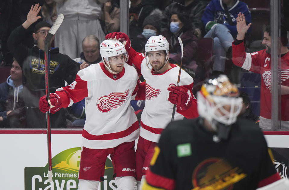 Detroit Red Wings' Pius Suter, back left, and Filip Zadina celebrate after Suter's goal against Vancouver Canucks goalie Collin Delia, front right, during the third period of an NHL hockey game in Vancouver, British Columbia, Monday, Feb. 13, 2023. (Darryl Dyck/The Canadian Press via AP)