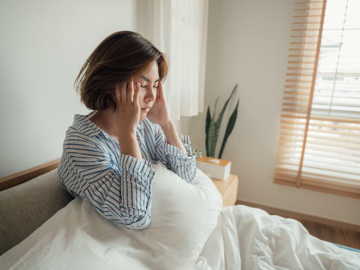 Young asian with high fever coughing and taking a medicine in the bed.