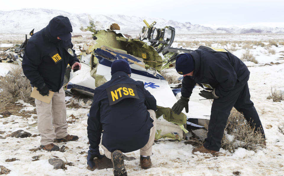 This photo provided by The National Transportation Safety Board shows NTSB investigators documenting the wreckage of a Pilatus PC-12 airplane at the crash site in Dayton, Nev., on Sunday, Feb. 26, 2023. A medical transport flight that crashed in a mountainous area in northern Nevada, killing five all five people aboard the plane including a patient, apparently broke apart before hitting the ground, authorities said Sunday. (NTSB via AP)