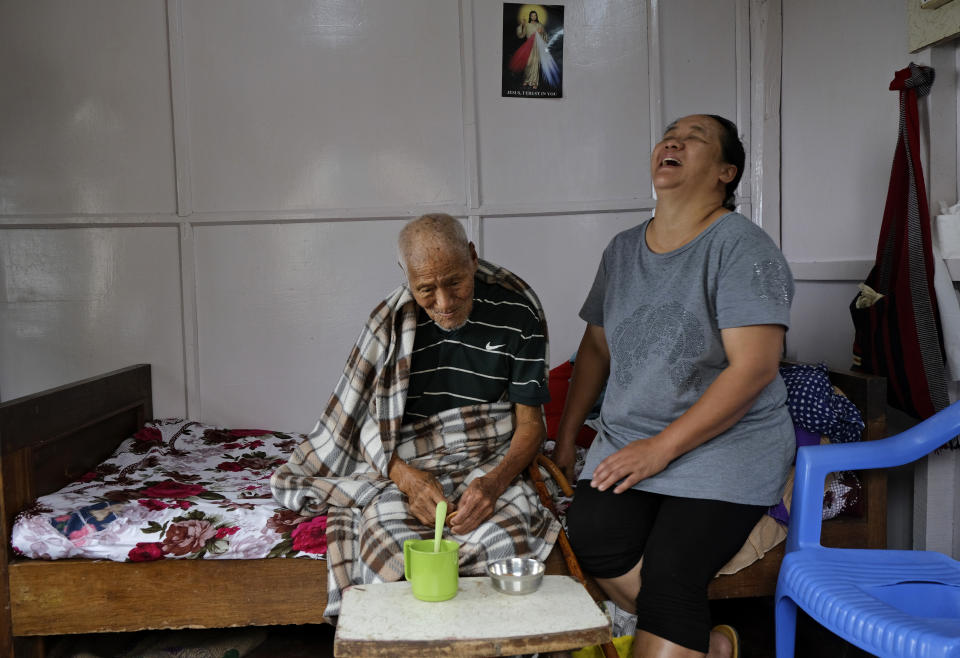 Vichuzo Rutsa, 101, shares a laugh with his daughter-in-law Nelly as he recounts memories of the bloody battle between the Japanese and British Commonwealth forces in his village during World War II, in Kohima village, India, Wednesday, Aug. 12, 2020. For the locals, World War II was a conflict brought to their quiet lands by outsiders, and along with it, immeasurable loss. A population that had never been exposed to life beyond the village saw battle tanks and fighter planes dropping bombs over their beloved land. "We really suffered during the war," Rutsa said softly from his bed. (AP Photo/Yirmiyan Arthur)