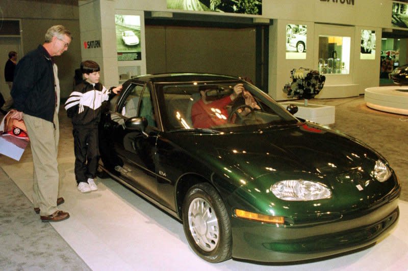 Visitors to the Greater St. Louis Auto Show examine the Saturn EV1 electric car on January 29, 1998. On January 4, 1996, General Motors announced it would begin mass selling an electric vehicle, the EV1, for the first time. File Photo by Bill Greenblatt/UPI