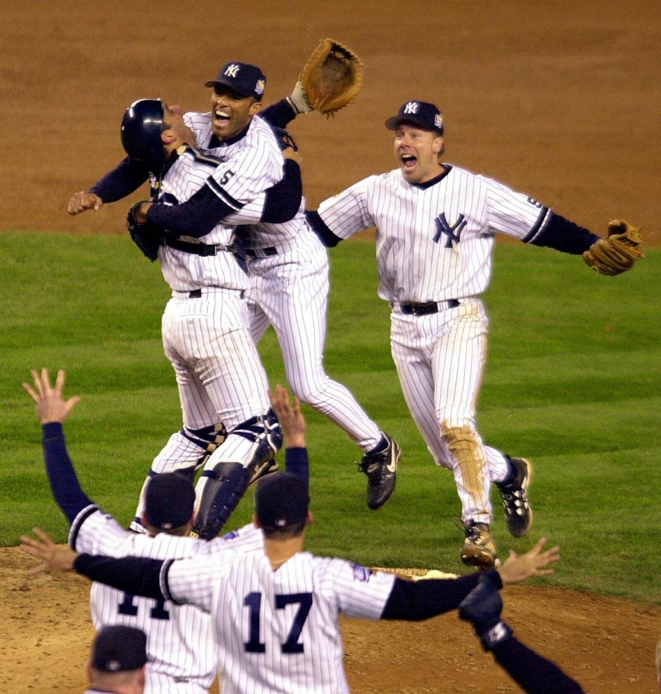 FILE - In this Oct. 27, 1999, file photo, New York Yankees catcher Jorge Posada, left rear, and third baseman Scott Brosius, right rear, rush pitcher Mariano Rivera as teammates run to the mound after the Yankees beat the Atlanta Braves 4-1 in Game 4 of the World Series to sweep the series in New York. Rivera will be inducted into the Baseball Hall of Fame on Sunday, July 21, 2019. (AP Photo/Ron Frehm, File)