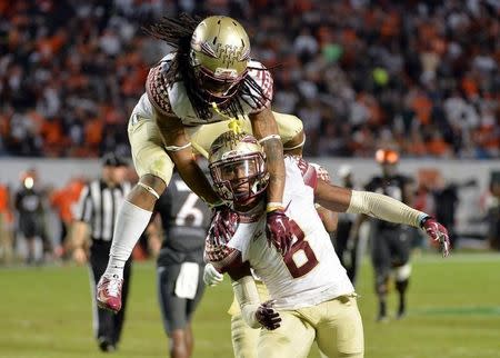 Nov 15, 2014; Miami Gardens, FL, USA; Florida State Seminoles cornerback Ronald Darby (top) celebrates after defensive back Jalen Ramsey (bottom) made an interception during the fourth quarter against Miami Hurricanes at Sun Life Stadium. FSU won 30-26. Mandatory Credit: Steve Mitchell-USA TODAY Sports