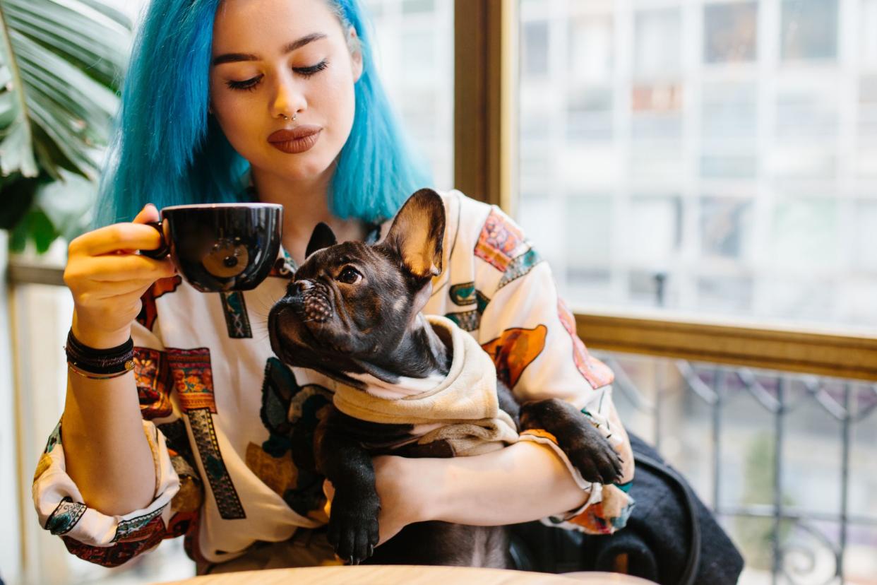 Young hipster woman in cafe with dog drinking coffee