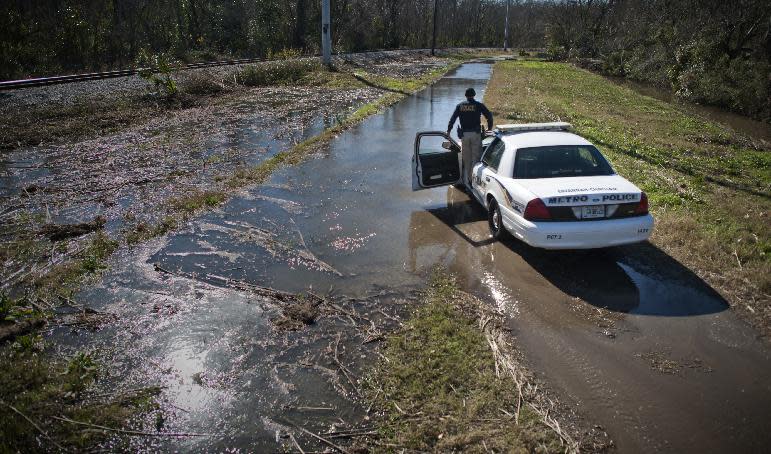 In this Friday, Jan. 3, 2014 photo, Homeless Liaison Officer Tom Gentner stands on the door frame of his police cruiser to check the depth of floodwaters blocking his access to one of the city's 20 homeless camps in Savannah, Ga. Several of the camps are in remote sections of town surrounding the historic district. After being awarded by the department for his work with the homeless, he will be assigned a new SUV for his job. (AP Photo/Stephen B. Morton)