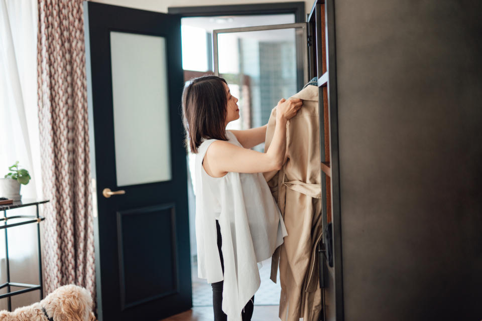 woman hanging coat in closet