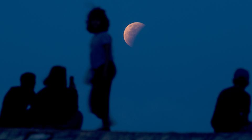 Residents watch the lunar eclipse at Sanur beach in Bali, Indonesia, on Wednesday, May 26, 2021.