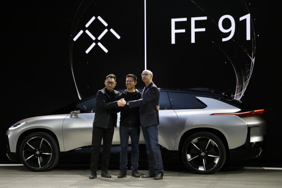 LeEco CEO YT Jia, center, poses with Nick Sampson, Faraday Future's senior vice president of product research & development, right, and Richard Kim, vice president of design, after unveiling the FF91 electric car at CES International Tuesday, Jan. 3, 2017, in Las Vegas. (AP Photo/Jae C. Hong)