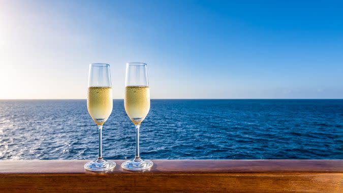 Side view of two glasses of sparkling wine on a wooden railing of a cruise ship.