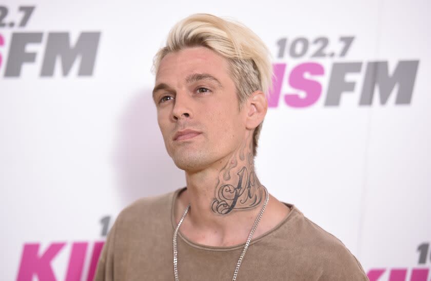 A blond man with a neck tattoo looks up