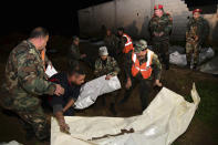 In this photo released Monday, Feb. 17, 2020 by the Syrian official news agency SANA, Syrian security forces check human remains at the site of a mass grave believed to contain the bodies of civilians and troops in Douma, near the Syrian capital Damascus. Syrian state media reported that authorities have exhumed nearly 70 bodies of civilians and soldiers including a woman, most of them shot at close range. (SANA via AP)