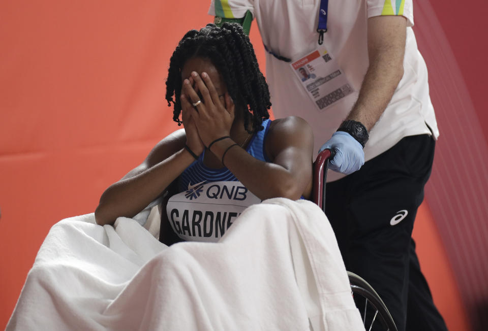 English Gardner, of the United States covers her face after getting injured in the women's 100 meter semifinal at the World Athletics Championships in Doha, Qatar, Sunday, Sept. 29, 2019. (AP Photo/Petr David Josek)