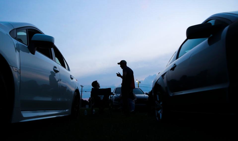 People chat as the sun goes down as car enthusiasts gather at Pit Daddy's BBQ outside Smyrna earlier this month.