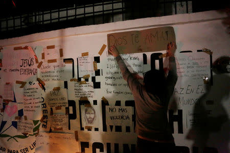 A girl puts up a sign reading "God loves you" outside the Colegio Americano del Noreste after a teenage student shot several students and a teacher at the private school before killing himself, in Monterrey, Mexico, January 18, 2017. REUTERS/Daniel Becerril