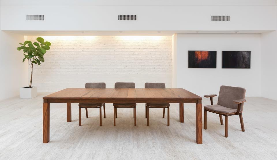 A dining table and chairs from the collection. Though Espasso's all-white Annex space can feel like a gallery, Junqueira isshowing Motta's furniture on rugs to give the items a homey feel.