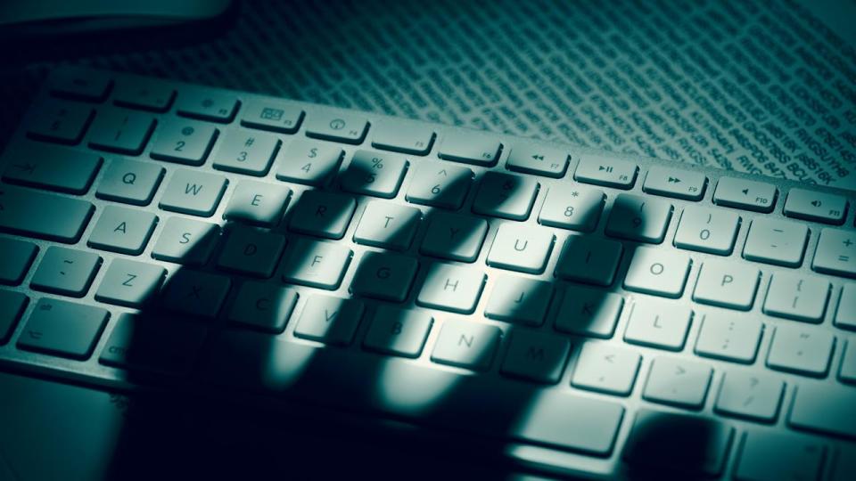 Data thiefÃ¢â‚¬â„¢s hand shadow on computer keyboard