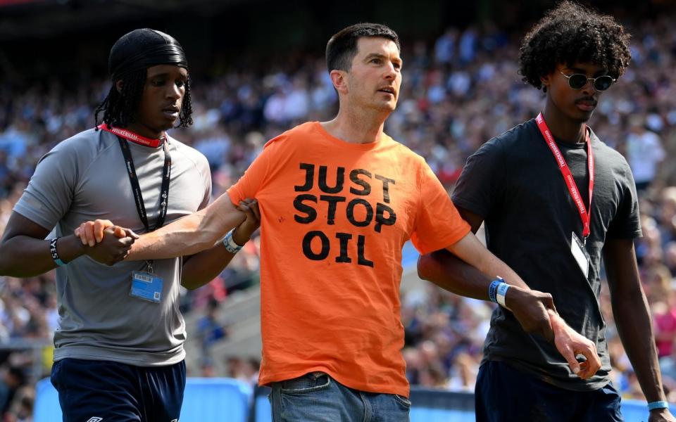 A 'Just Stop Oil' protestor is led off the pitch during the Gallagher Premiership Final between Saracens and Sale Sharks at Twickenham - Players and fans turn on Just Stop Oil protesters as Premiership Rugby final interrupted - Getty Images/Mike Hewitt