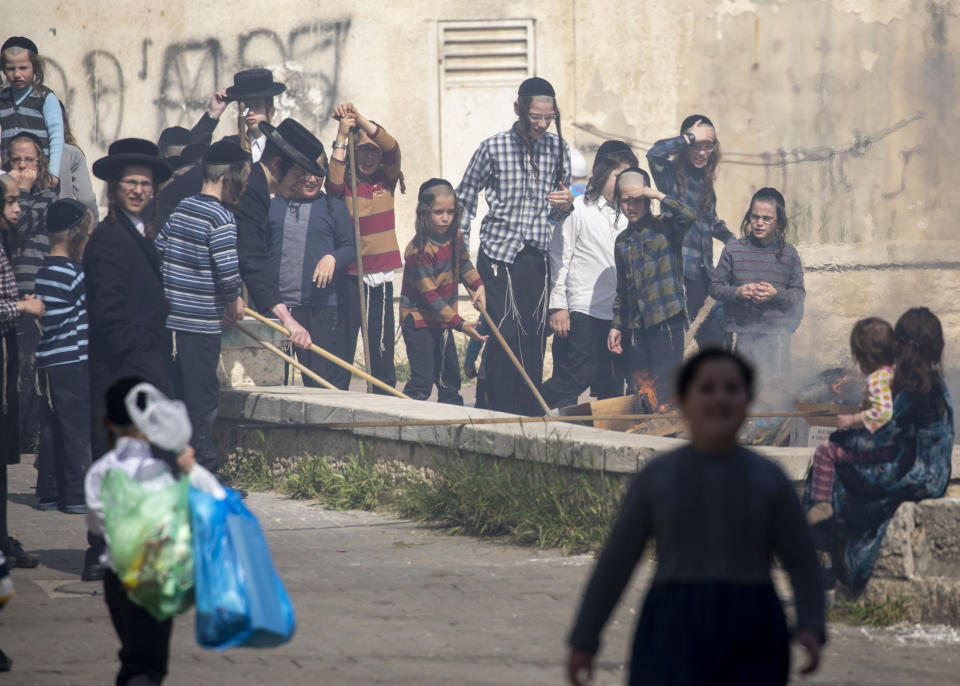 Ultra-Orthodox Jewish children burn leavened items in final preparation for the Passover holiday in the Orthodox neighborhood of Mea Shearim in Jerusalem, Wednesday, April 8, 2020. Jerusalem authorities have said they will gather the bread and burn it in a big bonfire in one location to avoid large gatherings. But, some in the Mea Shearim neighbourhood shunned the orders. Many of Israel's ultra-Orthodox residents, obeying their religious leaders, have ignored pleas to stay home in the face of the coronavirus threat. Israeli Prime Minister Benjamin Netanyahu announced Monday a complete lockdown over the upcoming Passover holiday to control the country's coronavirus outbreak, but offered citizens some hope by saying he expects to lift widespread restrictions after the week-long festival. Passover begins on sundown Wednesday. (AP Photo/Ariel Schalit)