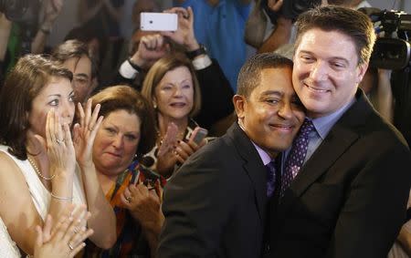 Same-sex couple Todd and Jeff Delmay (R) embrace as Catherina Pareto (L) looks on as they get married at the Eleventh Judicial Circuit Court of Florida in Miami, Florida, January 5, 2015. REUTERS/Javier Galeano