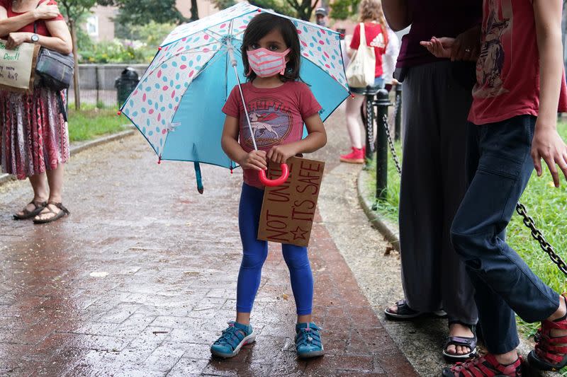 A child attends a rally to protest the opening of schools