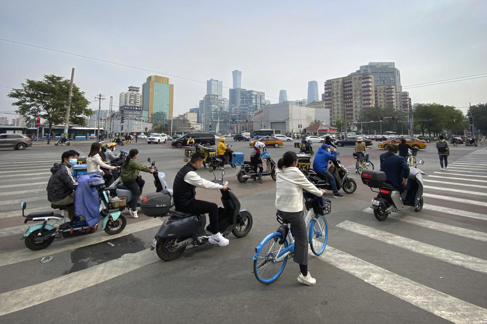 People riding scooters and bicycles wait at an intersection in the central business district in Beijing, Wednesday, Oct. 12, 2022. A meeting of the ruling Communist Party to install leaders gives President Xi Jinping, China's most influential figure in decades, a chance to stack the ranks with allies who share his vision of intensifying pervasive control over entrepreneurs and technology development. (AP Photo/Mark Schiefelbein)